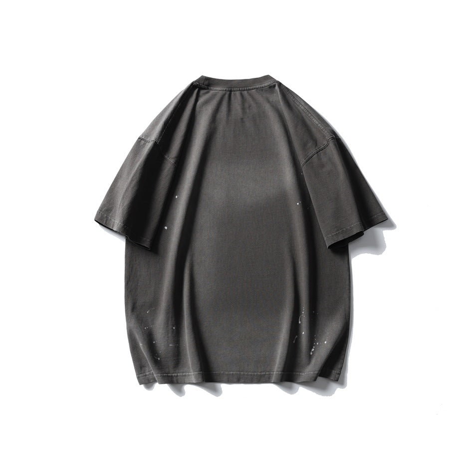 Back of an oversized charcoal gray short-sleeve T-shirt with small white paint-like splatters near the sides and hem.