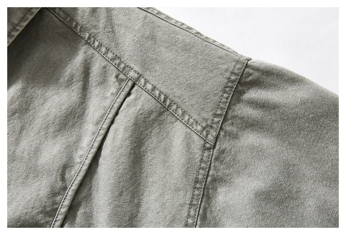 Close-up of stitched seams across the gray-green jacket's shoulder and upper back.