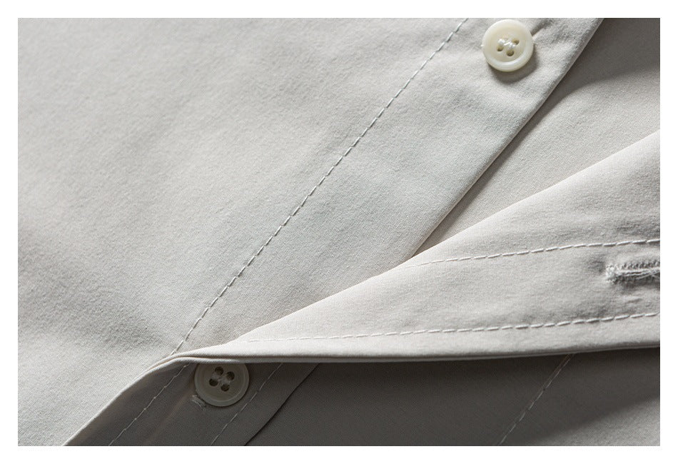 Close-up of light gray fabric with stitched seams and two cream buttons.
