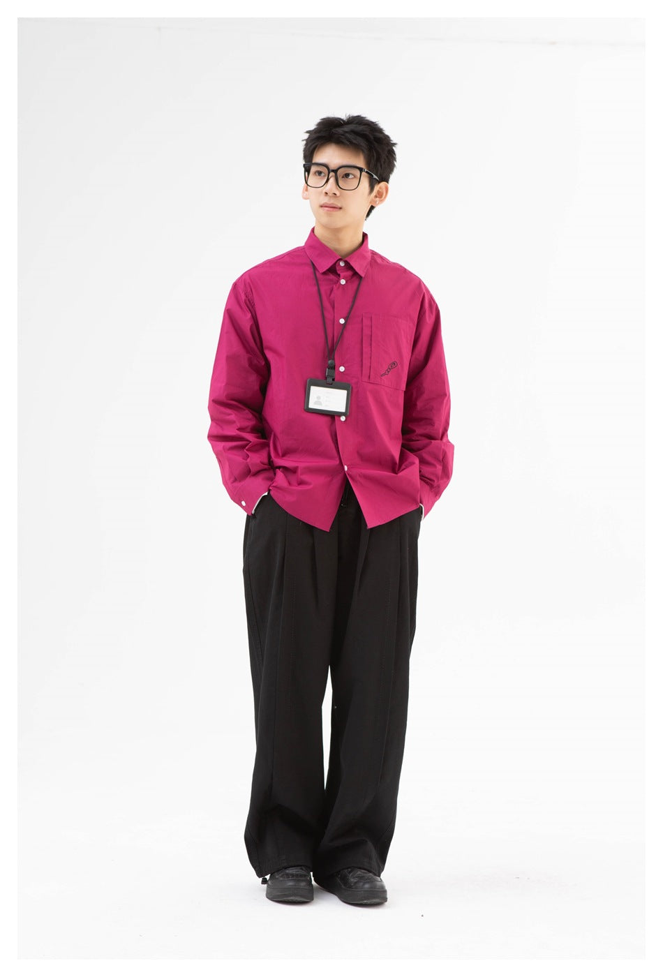 Full-length front view of a model in a bright magenta button-up shirt and wide black trousers.