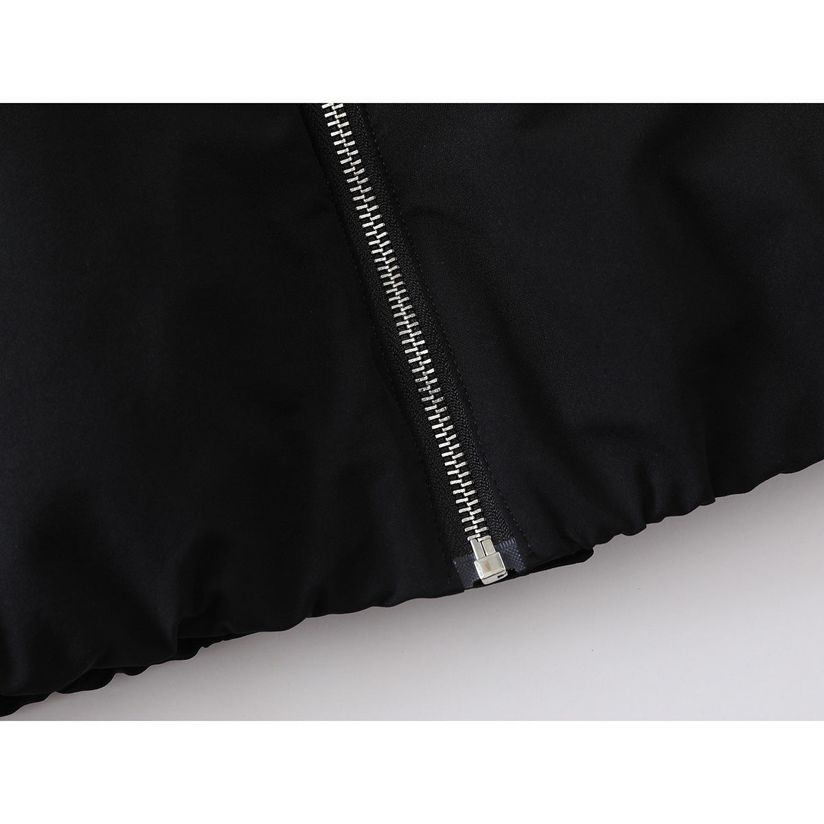 Close-up of the black jacket’s silver zipper at the gathered hem.