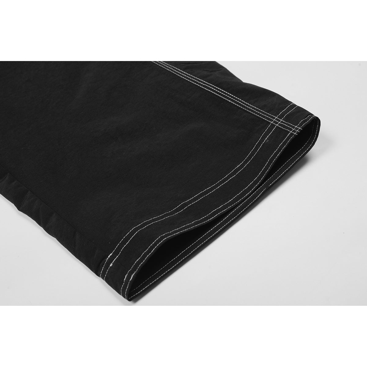Close-up of a black pant leg hem with multiple rows of white contrast stitching.