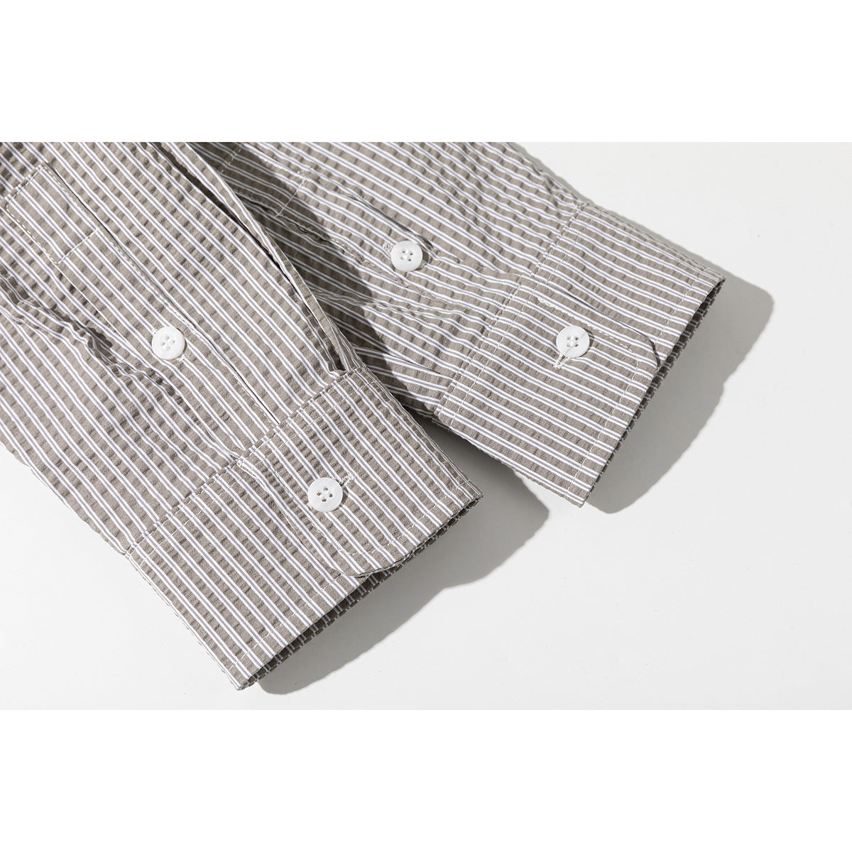 Close-up of the striped shirt's long sleeve cuffs with white buttons.
