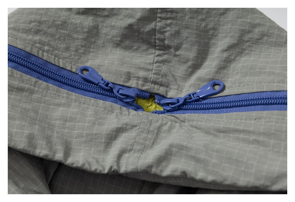 Close-up of a blue two-way zipper on gray grid-patterned fabric.