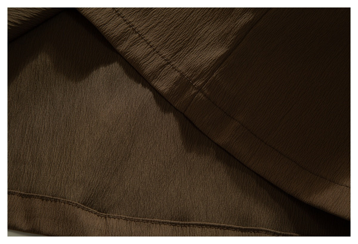 Close-up of brown garment fabric folded to show an inner seam and stitching.
