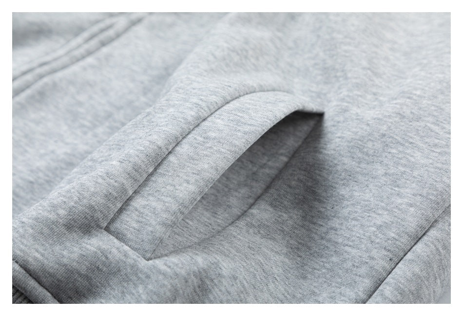 Close-up of a slanted welt pocket on heather gray hoodie fabric.