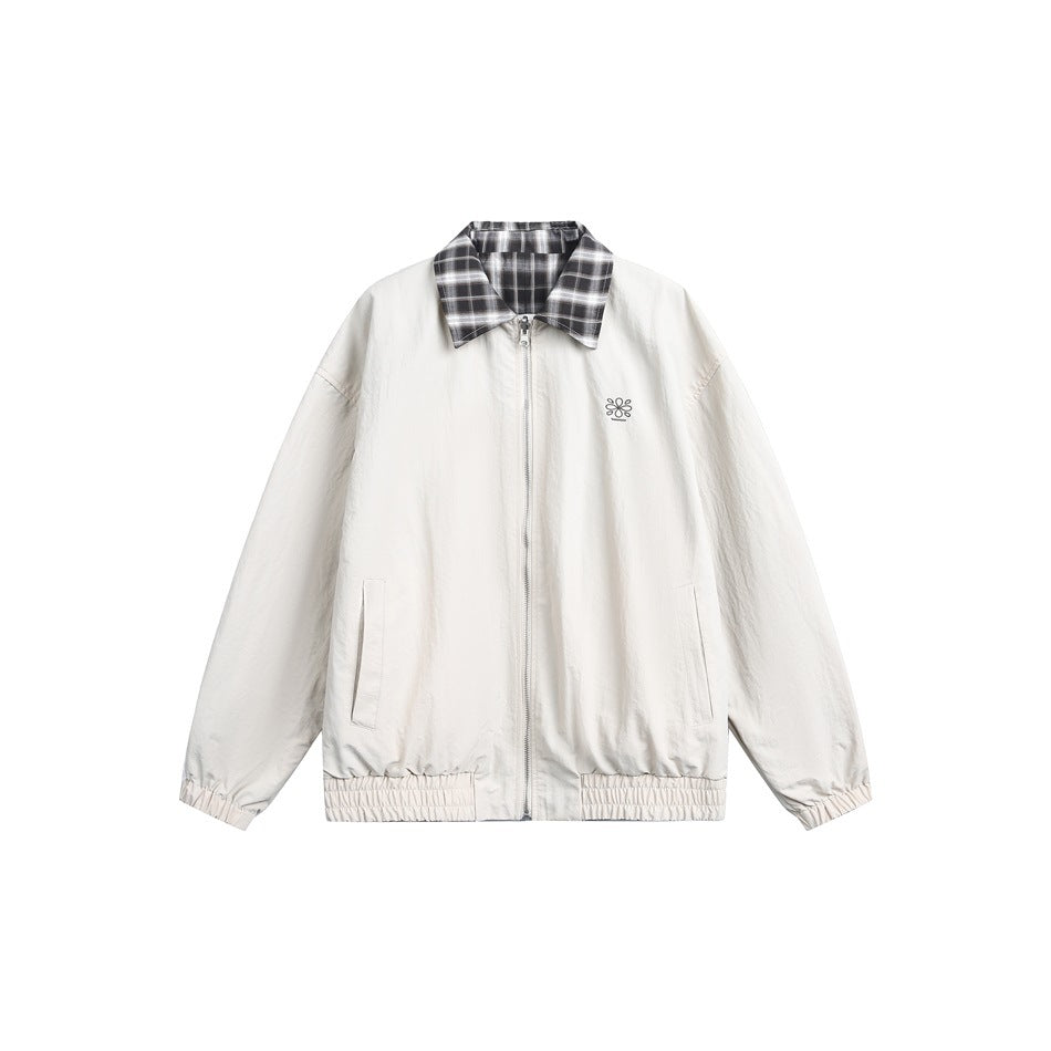Front view of a cream zip jacket with a plaid collar, small chest embroidery, slanted pockets, and gathered cuffs and hem.