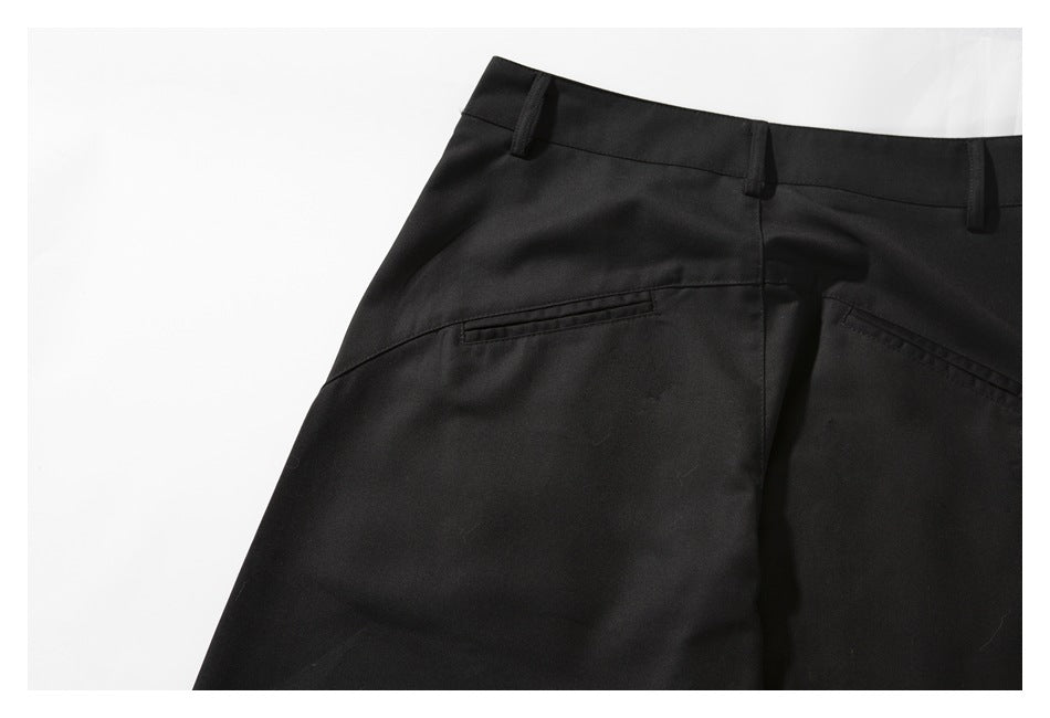 Close-up of the back of black trousers, showing the waistband, belt loops, and welt pockets.