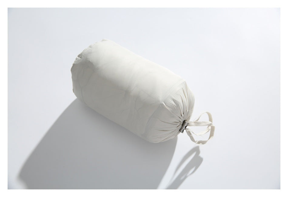 Ivory garment compactly packed in a matching cylindrical drawstring pouch.