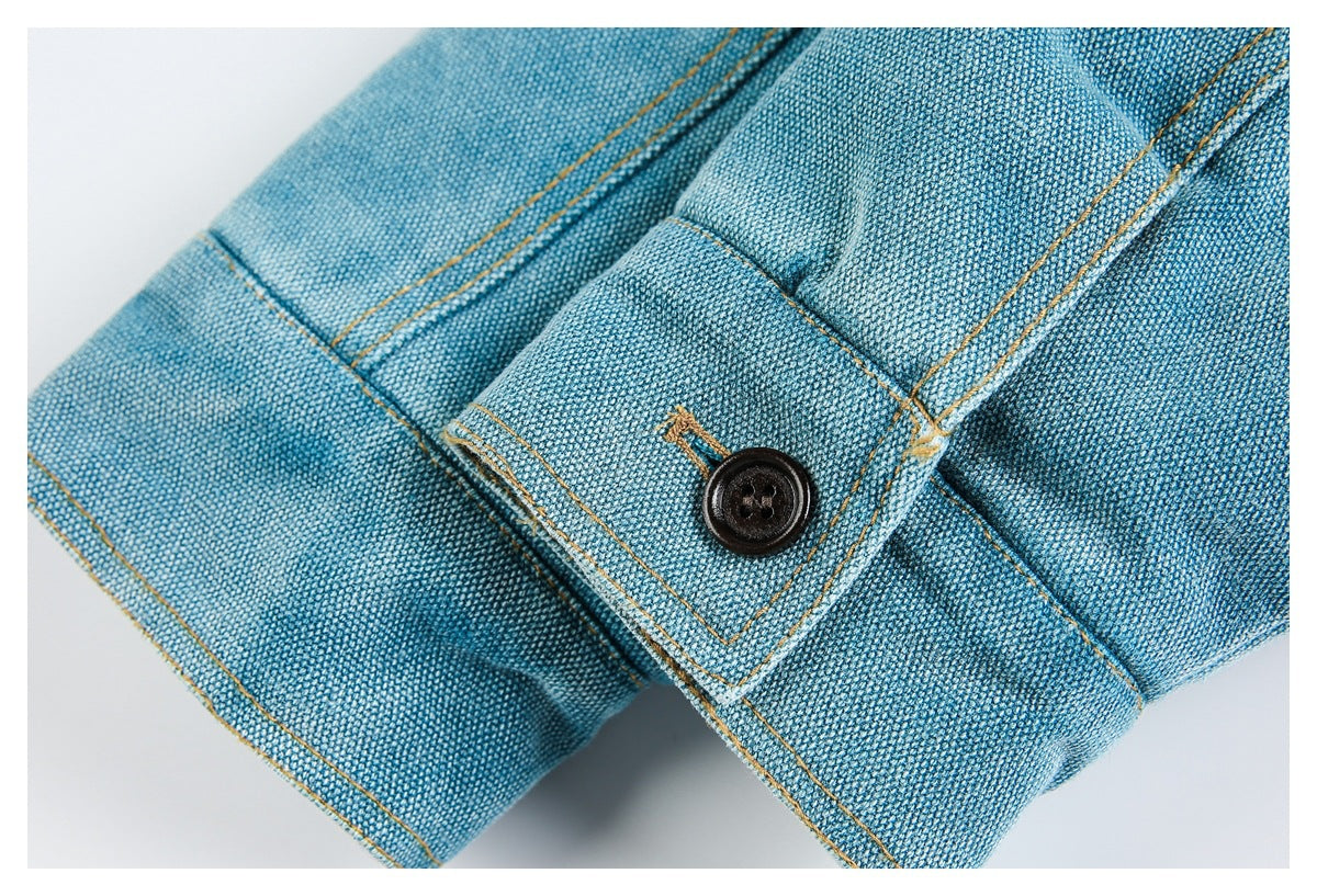 Close-up of a blue woven sleeve cuff with a dark button and ochre stitching.