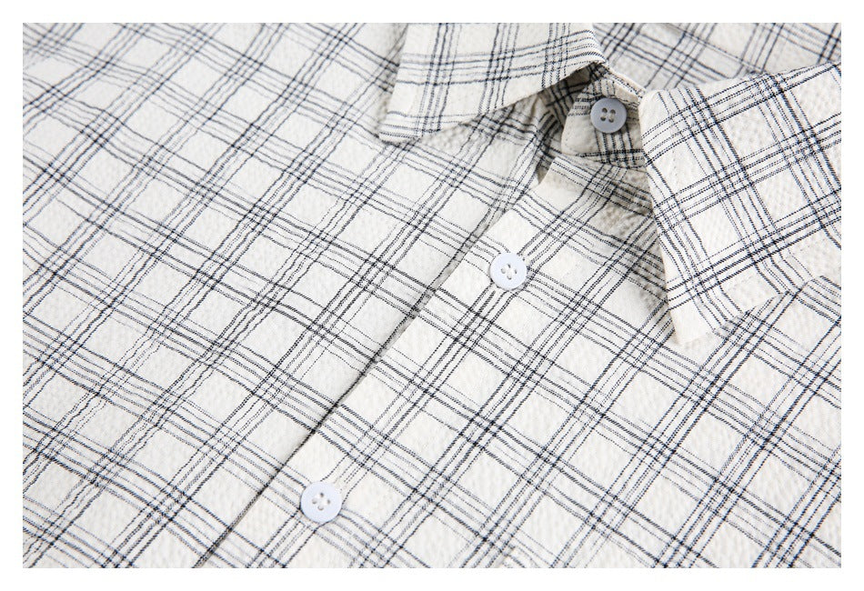 Close-up of the collar, buttons, and plaid pattern on an ivory button-up shirt.