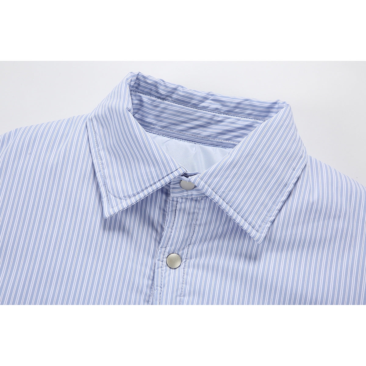 Close-up of a pointed collar and upper placket on a light blue and white striped shirt jacket.