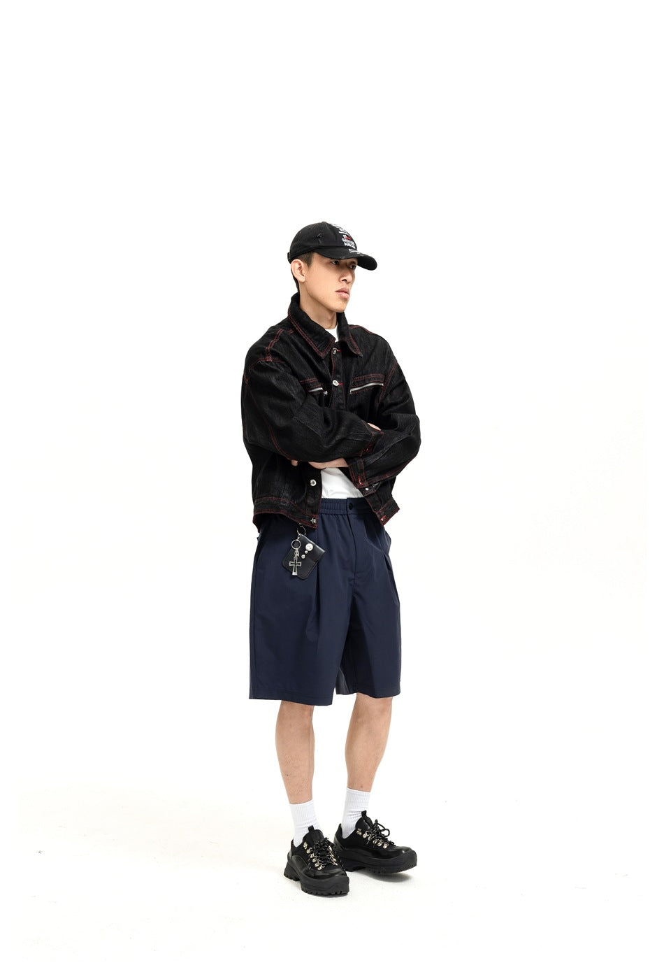 Full-length front view of a model wearing a black denim jacket with red stitching and navy shorts.