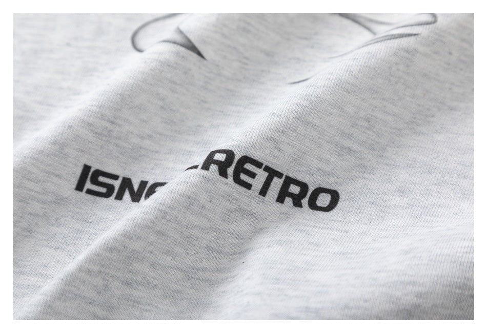 Close-up of black lettering and part of an abstract graphic on light heather gray T-shirt fabric.
