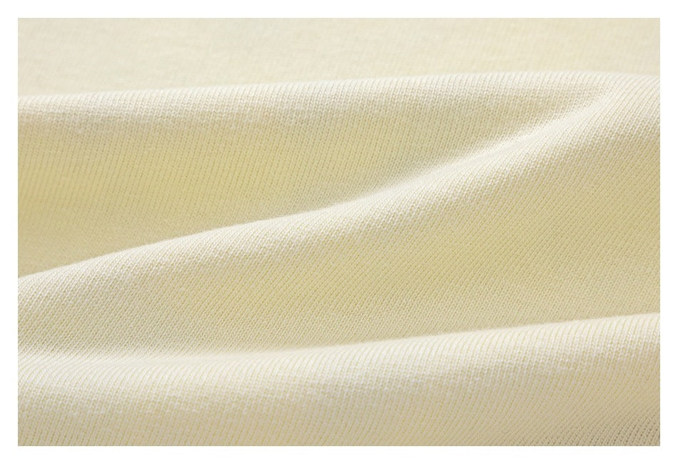 Close-up of ivory knit fabric draped to show its fine surface texture.