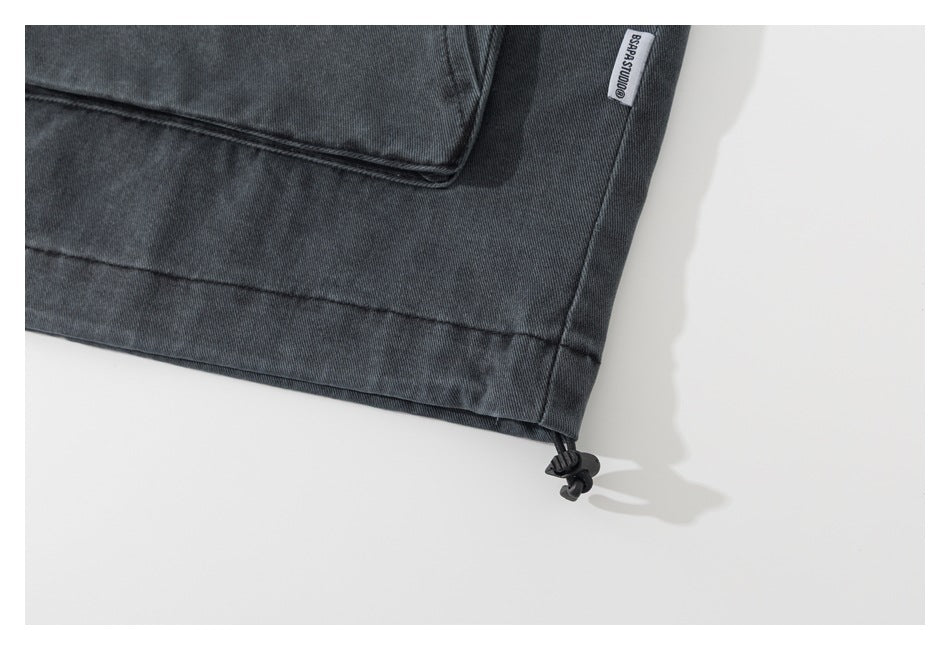 Close-up of a charcoal jacket hem with an adjustable drawcord and small sewn label.