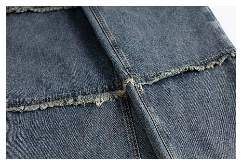 Close-up of blue-gray jeans with a frayed raw hem and visible contrast stitching.