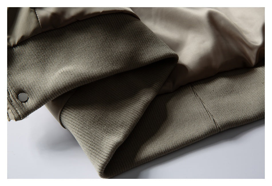 Close-up of the taupe jacket's ribbed cuff and hem with a metal snap fastener.
