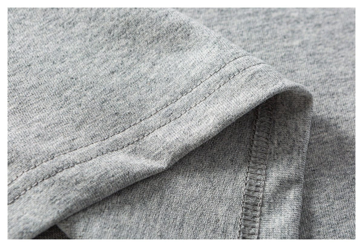 Close-up of stitching and an overlocked seam on heather gray shirt fabric.