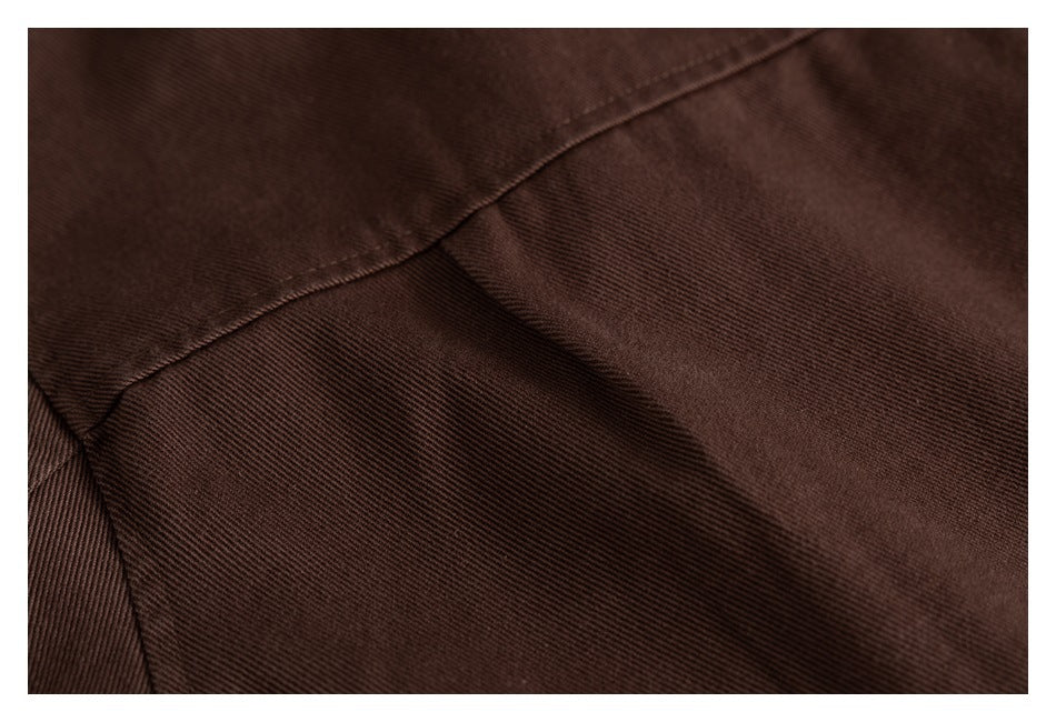 Close-up of stitching and a curved seam on dark brown jacket fabric.