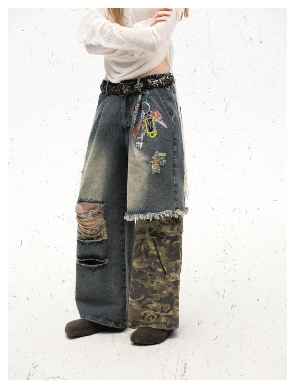 Model wearing wide-leg ripped blue jeans with a camouflage cargo leg panel, studded belt and key charms, cropped at the waist