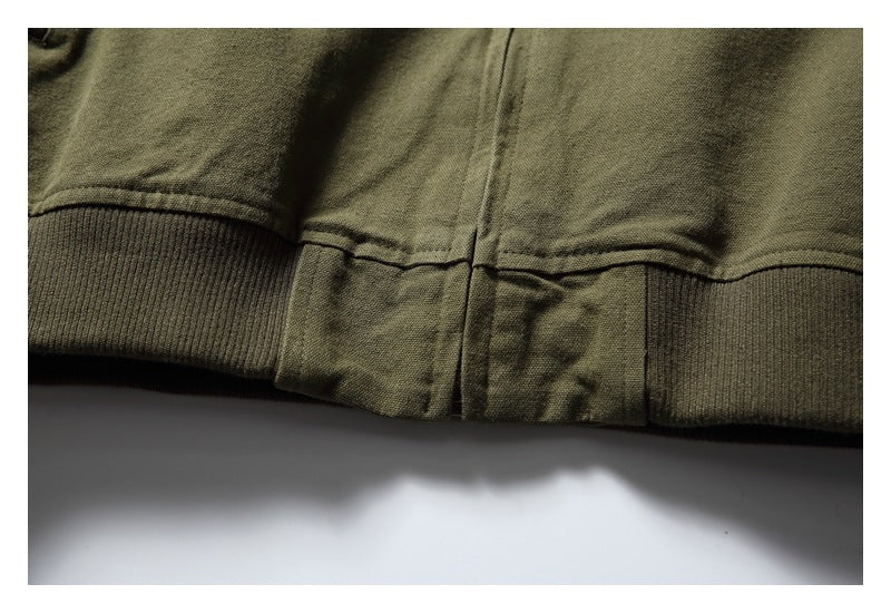 Close-up of an olive garment's lower hem with a central vertical seam and ribbed side bands.