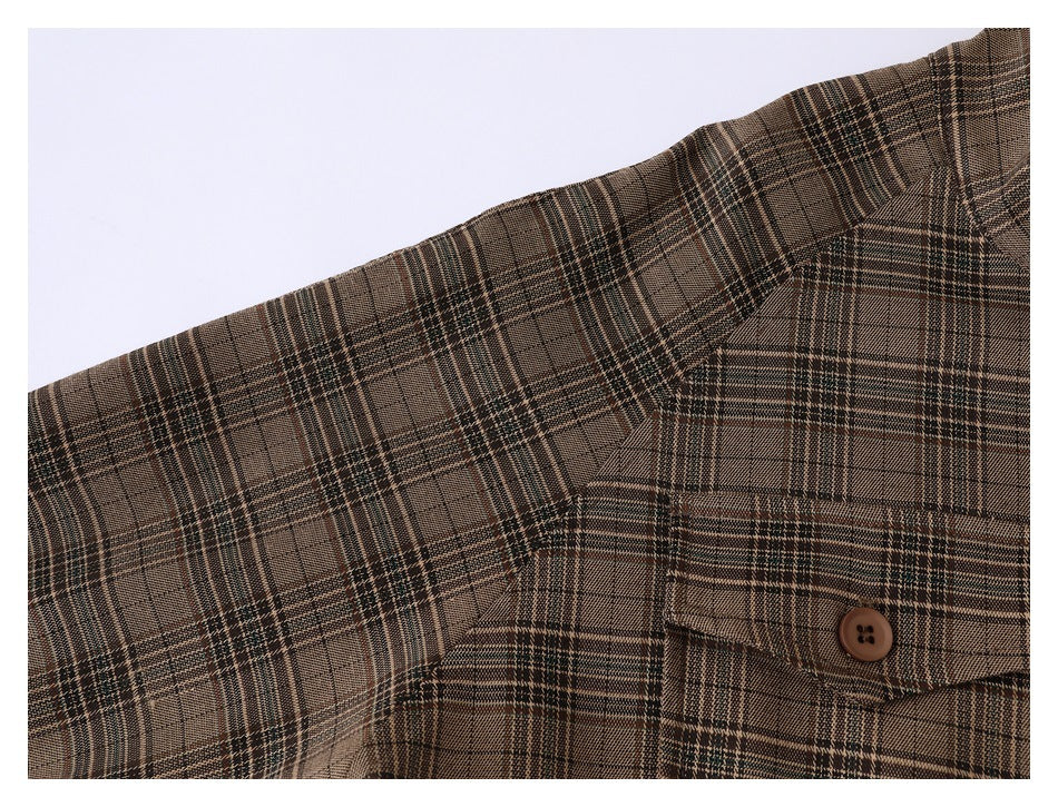 Close-up of a brown plaid jacket shoulder, sleeve, and buttoned chest pocket.