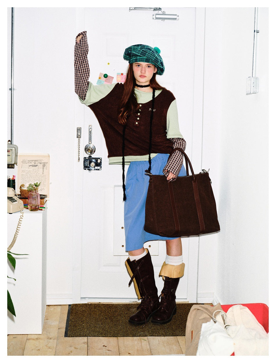 Model wearing the coffee brown layered top with plaid sleeves, blue skirt, beret, boots and large brown bag