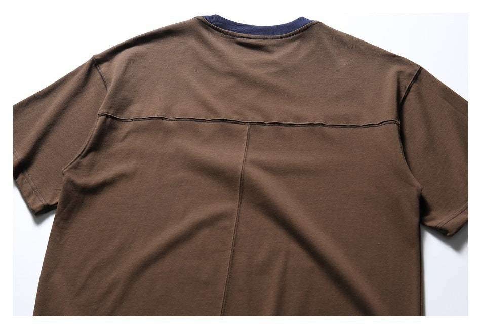 Back view of a brown short-sleeve T-shirt with a navy ribbed neckline, horizontal yoke seam, and center seam.
