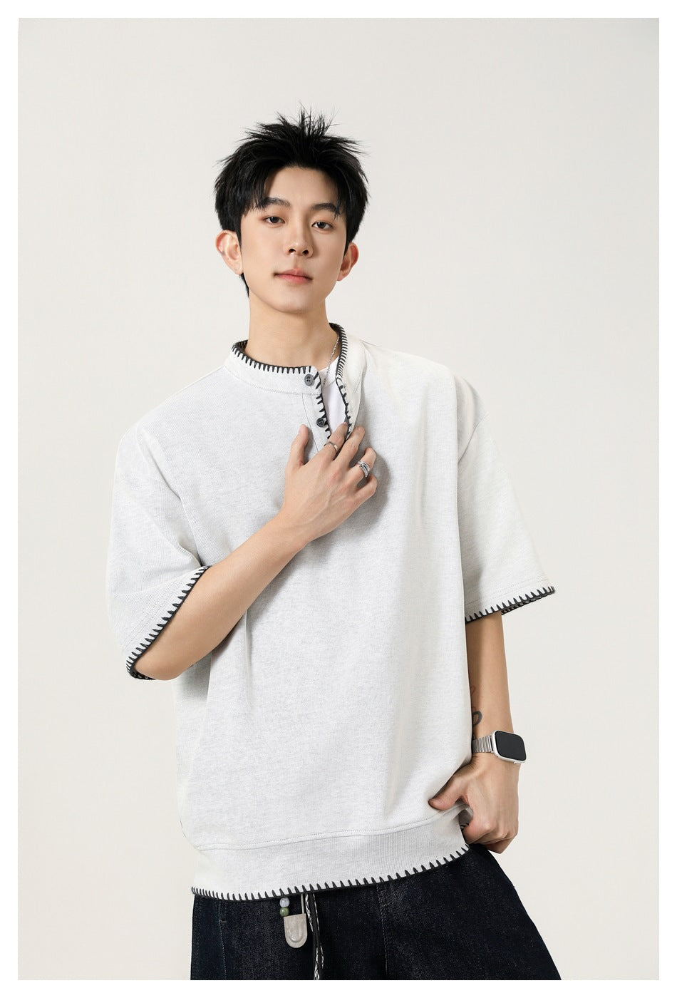 Man wearing light gray short-sleeve Henley top with dark whipstitch edges, close-up of neckline and sleeves