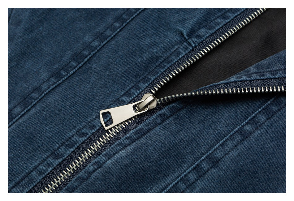 Close-up of a silver zipper on dark blue denim fabric.