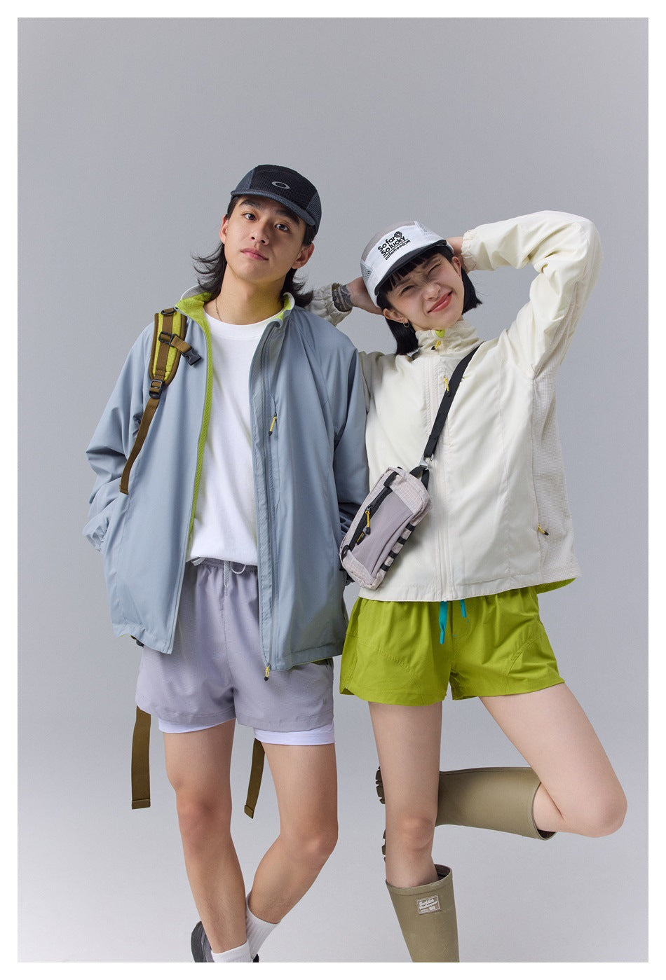 Two models in outdoor outfits: one wears an ivory jacket and lime shorts; the other wears a blue-gray jacket and pale shorts.