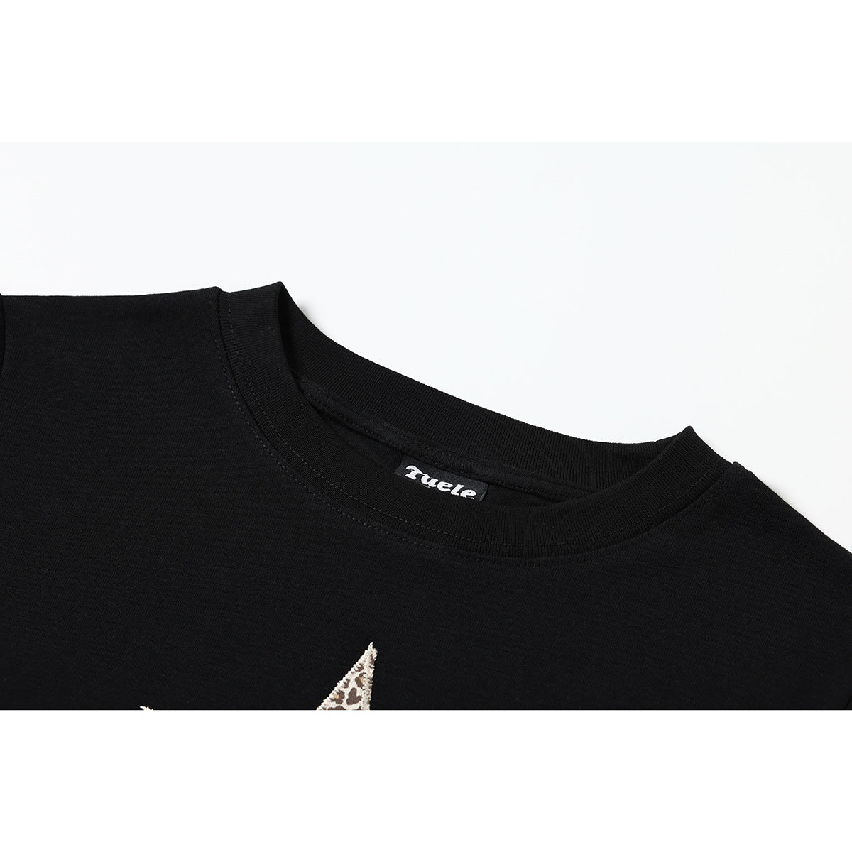 Close-up of a black crew-neck T-shirt collar and neck label, with the tip of a patterned star graphic visible below.