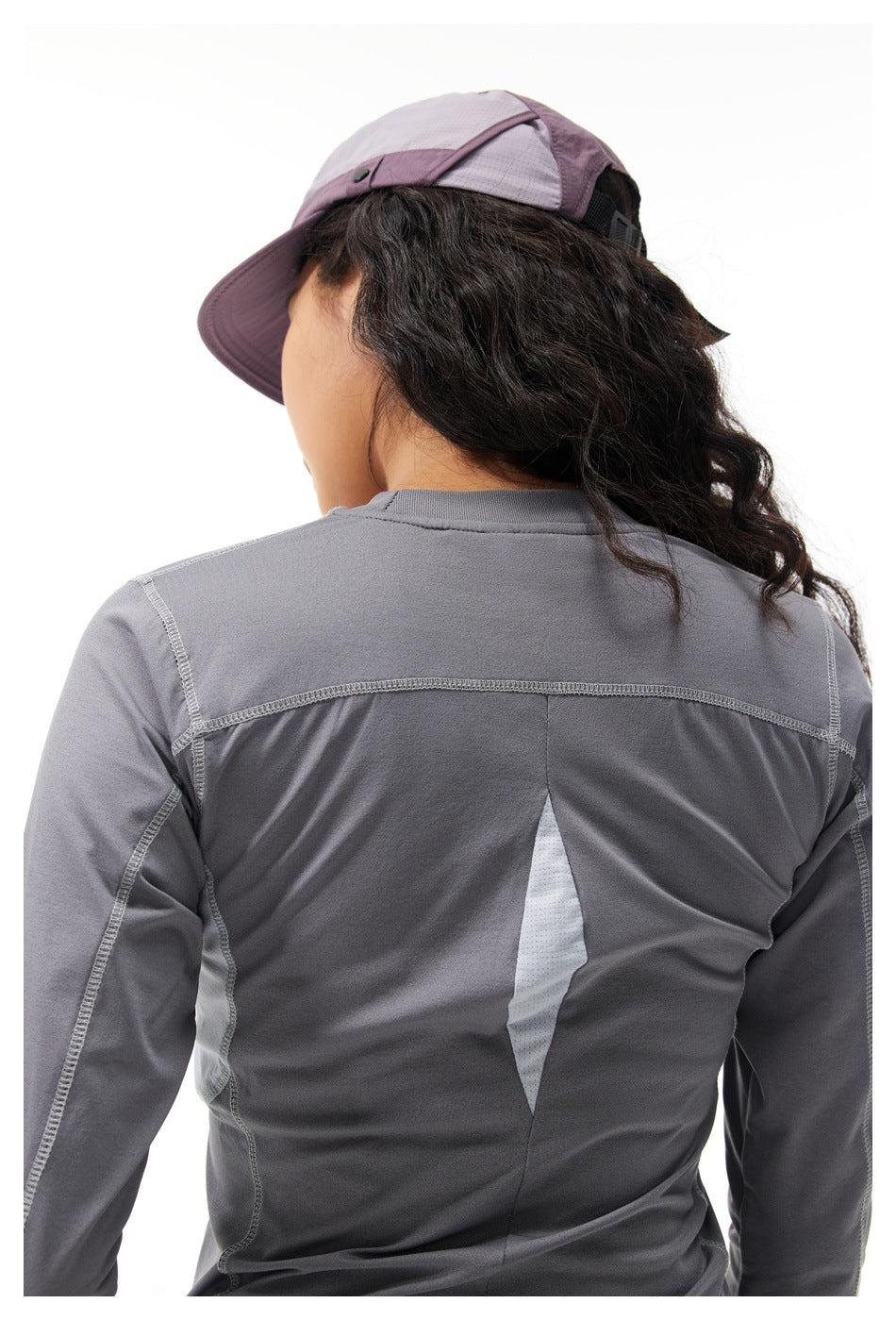 Back view of a model wearing a gray long-sleeve top with a pale mesh ventilation panel and stitched seams.