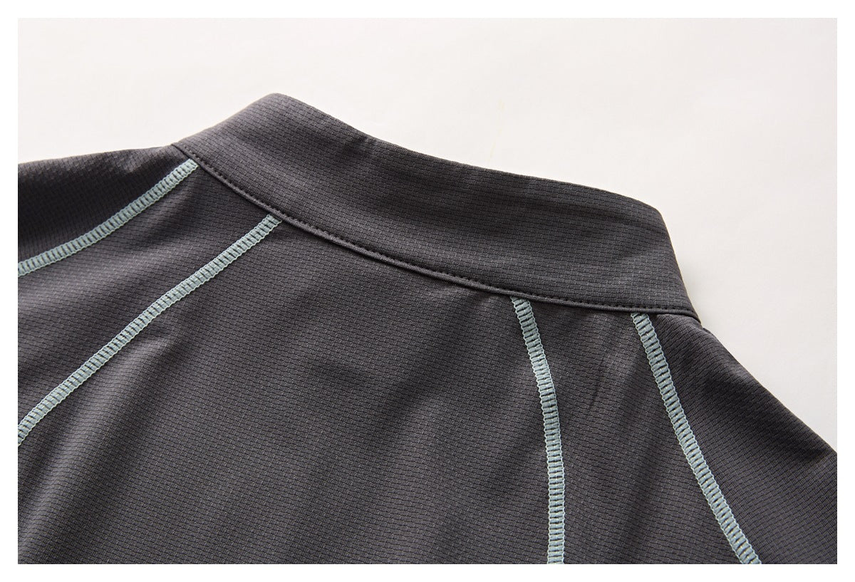Close-up of a dark charcoal garment collar and curved seams finished with pale gray-blue stitching.