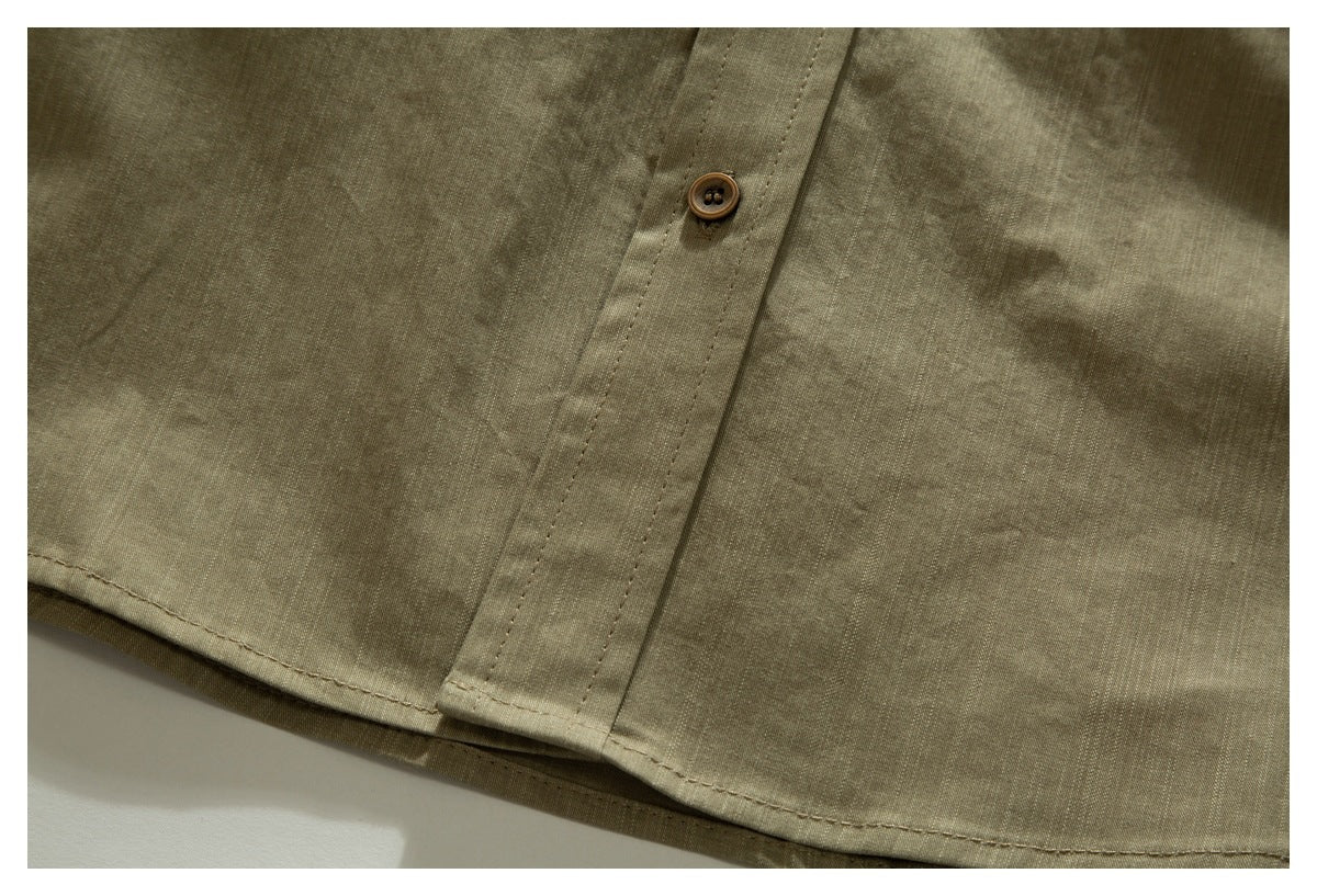 Close-up of an olive-khaki shirt's lower front, showing a buttoned placket and stitched hem.