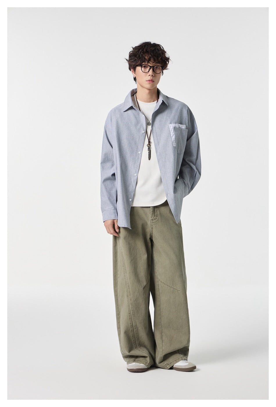 Model wearing a gray button-up shirt with checked chest pocket trim and olive wide-leg pants.