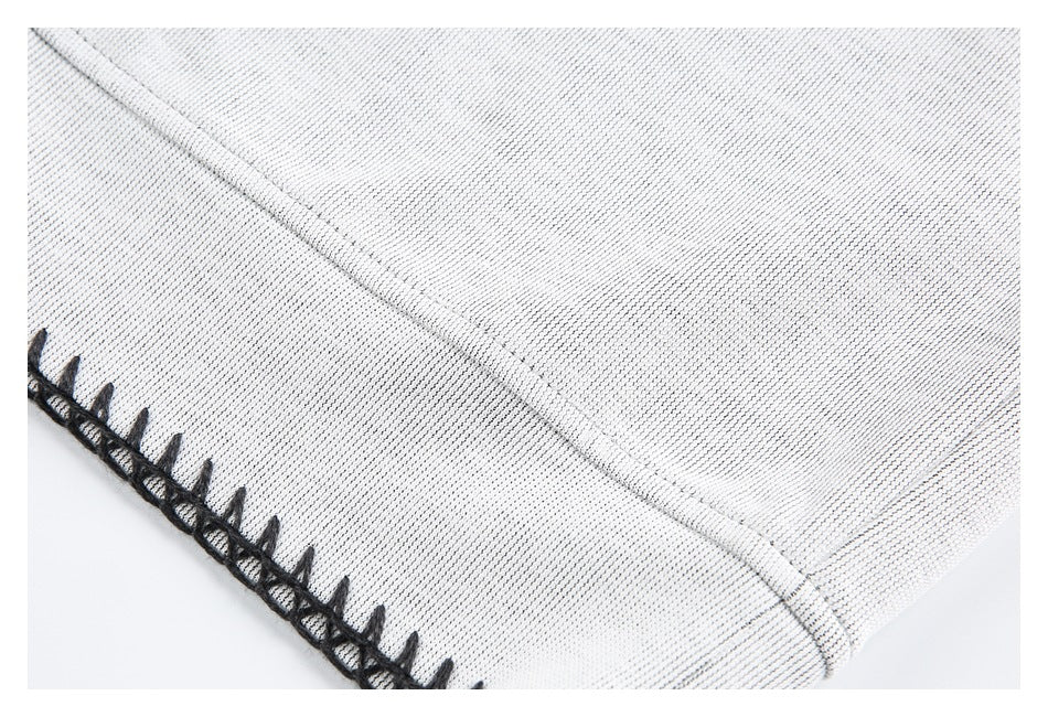 Close-up of a light gray garment seam and edge finished with black blanket stitching.