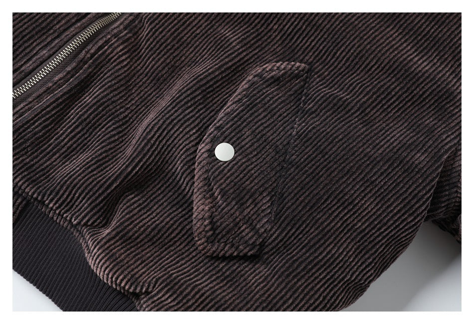 Close-up of a dark ribbed jacket front with a zip and snap-button flap pocket.