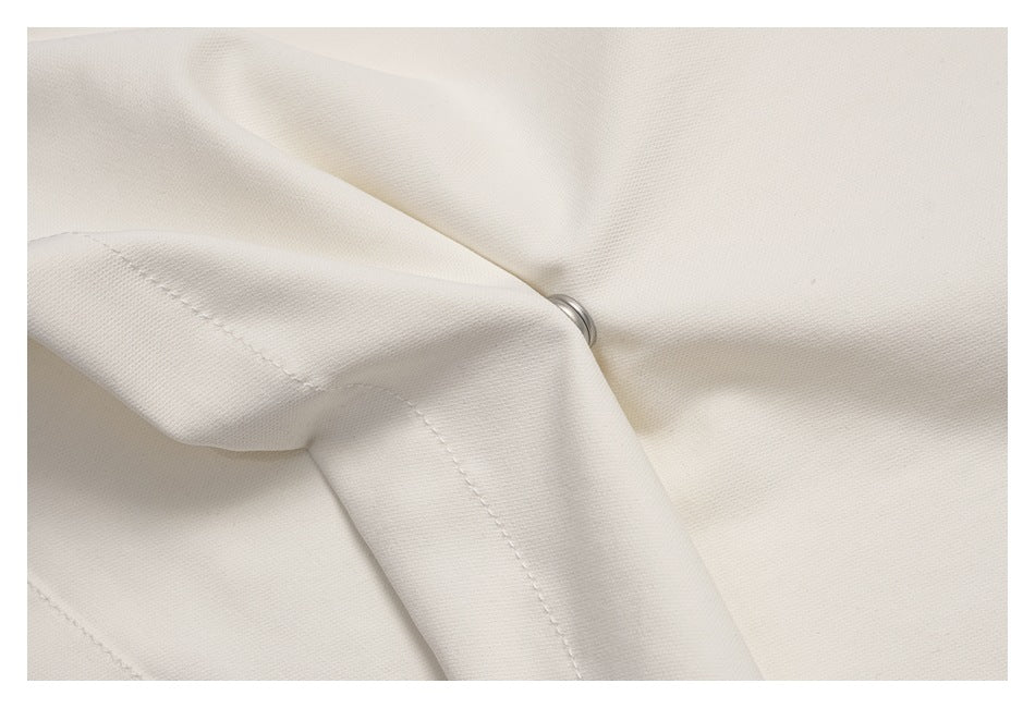Close-up of folded cream fabric with stitching and a partially visible metal fastener.