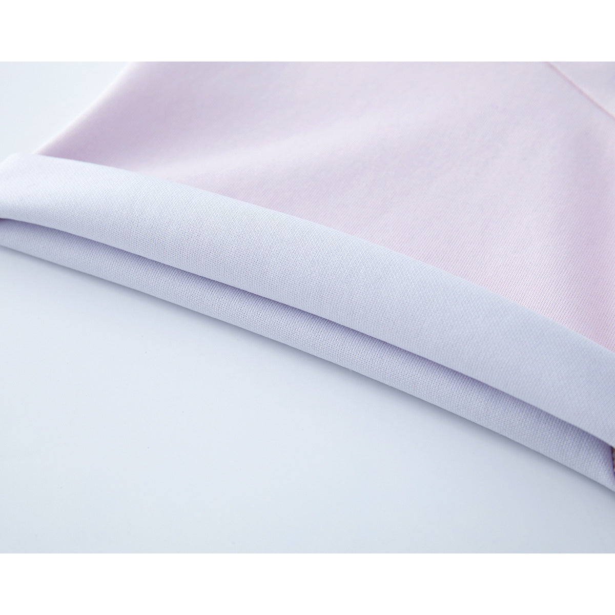 Close-up of the white folded hem and pale pink fabric of a T-shirt.