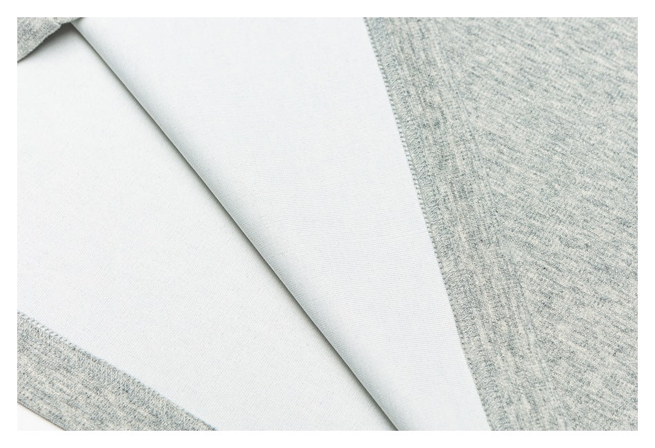 Close-up of the pale reverse side and overlocked seam of light gray heathered fabric.