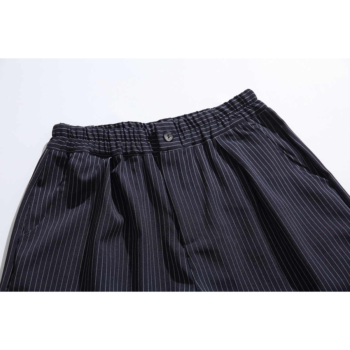 Close-up of dark navy pinstripe shorts showing the elasticated waistband, button, pleats and front pockets.