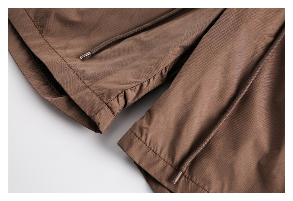 Close-up of brown shorts showing stitched edges and drawcords with metal tips.