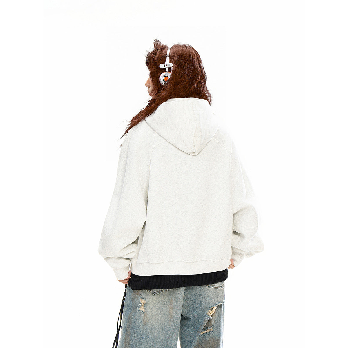Rear view of a model wearing a light gray oversized hoodie with a large hood and raglan sleeves.