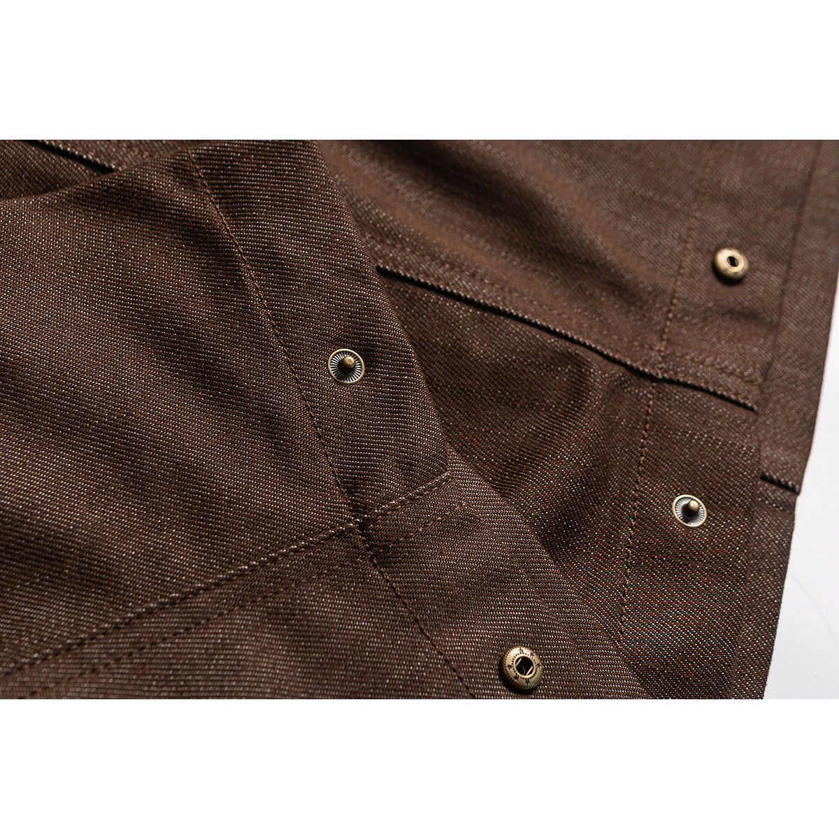 Close-up of brown trouser fabric, seams, and several round metal snap fasteners.