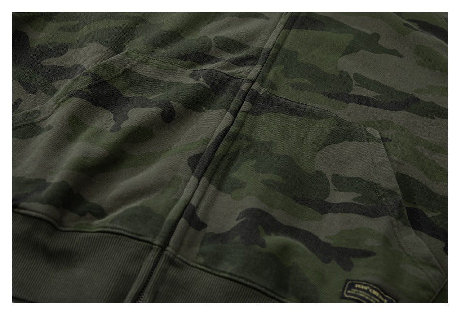Close-up of the front zipper, kangaroo pocket, and ribbed hem on an olive camouflage hoodie.
