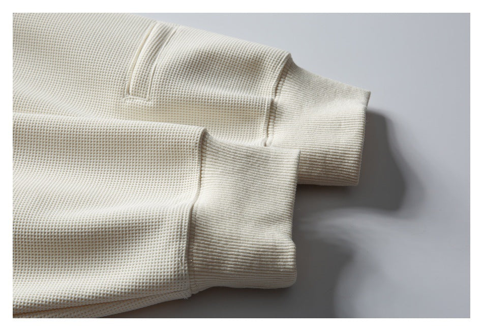 Close-up of a cream waffle-knit garment showing two wide ribbed cuffs and seam details.