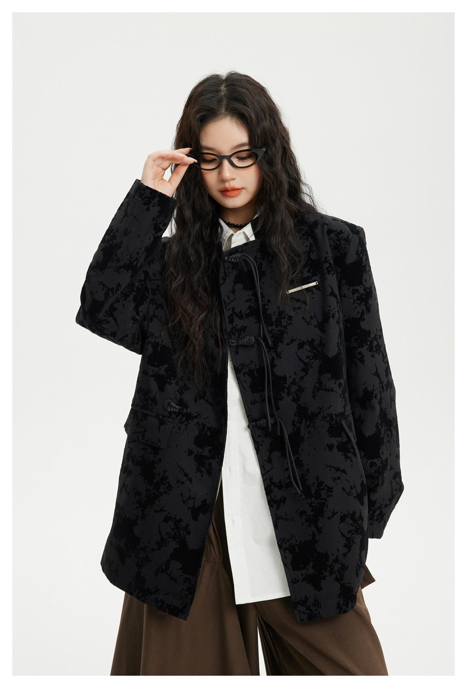 Closer front view of a model in a black abstract-patterned jacket with cord toggles, flap pockets and a small metal chest