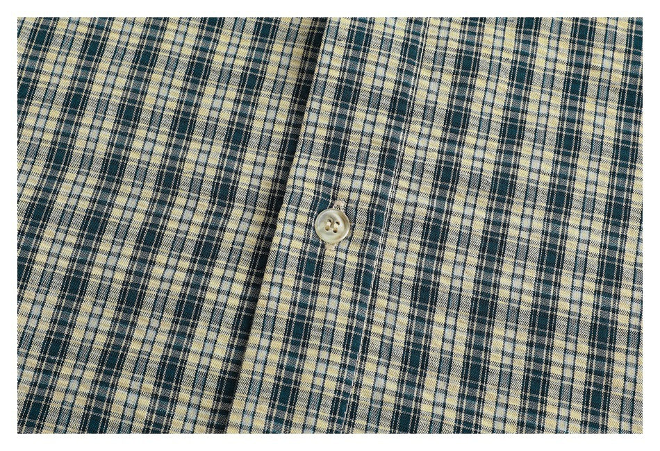 Close-up of the cream and dark plaid shirt fabric and a light-colored button.